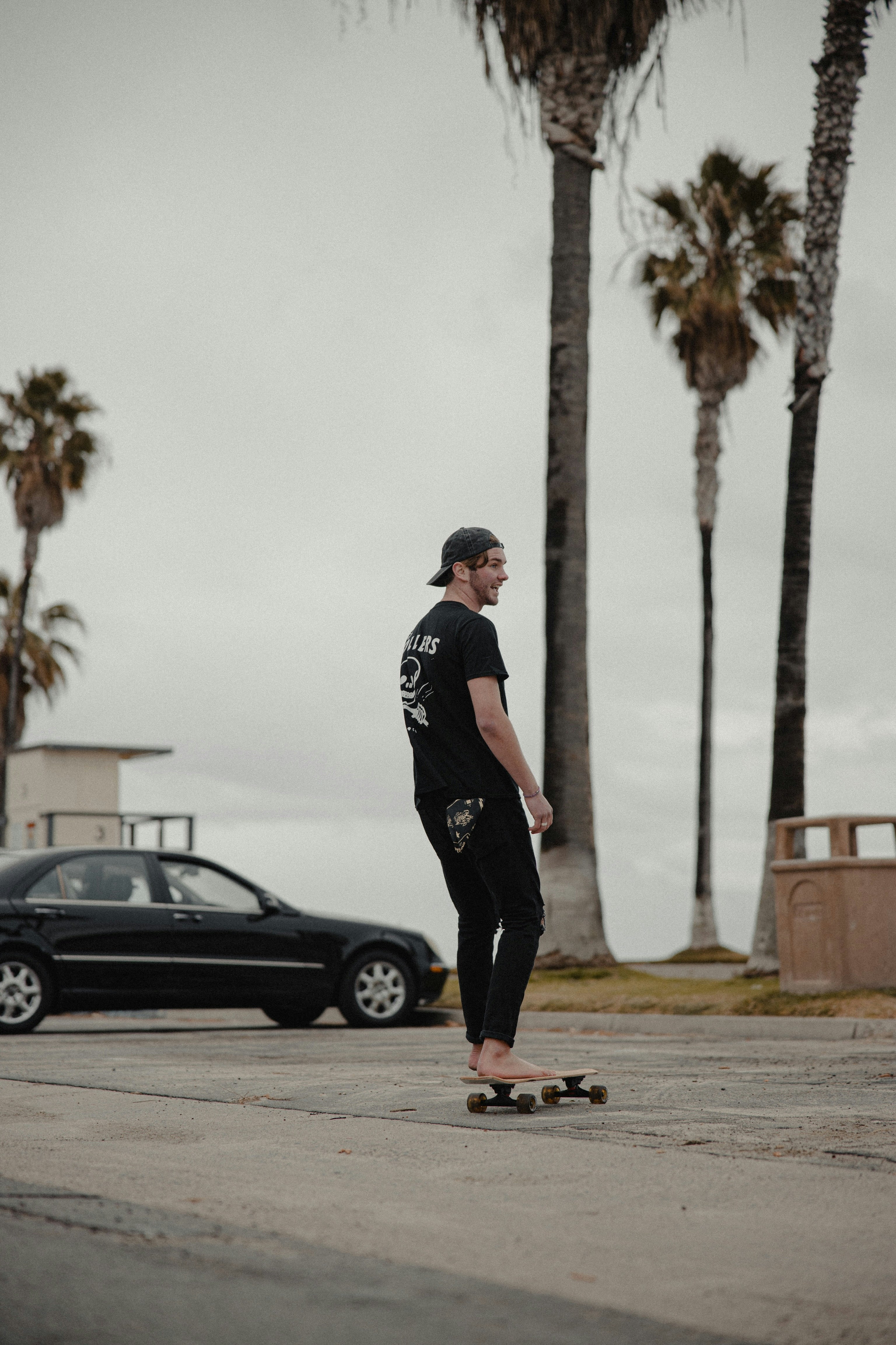 man in black and white crew neck t-shirt and black pants standing beside black car